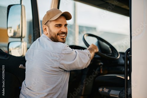Foto Happy professional driver entering in truck cabin and looking at camera