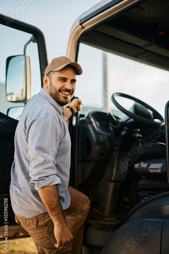 Fotografia Happy truck driver entering in vehicle cabin and looking at camera