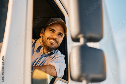 Happy truck driver looking through side window while driving his truck.