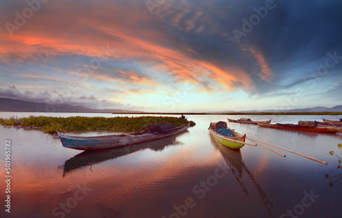 Traditional wooden boats anchored in Limboto Lake at sunset, Gorontalo, Indonesia photo