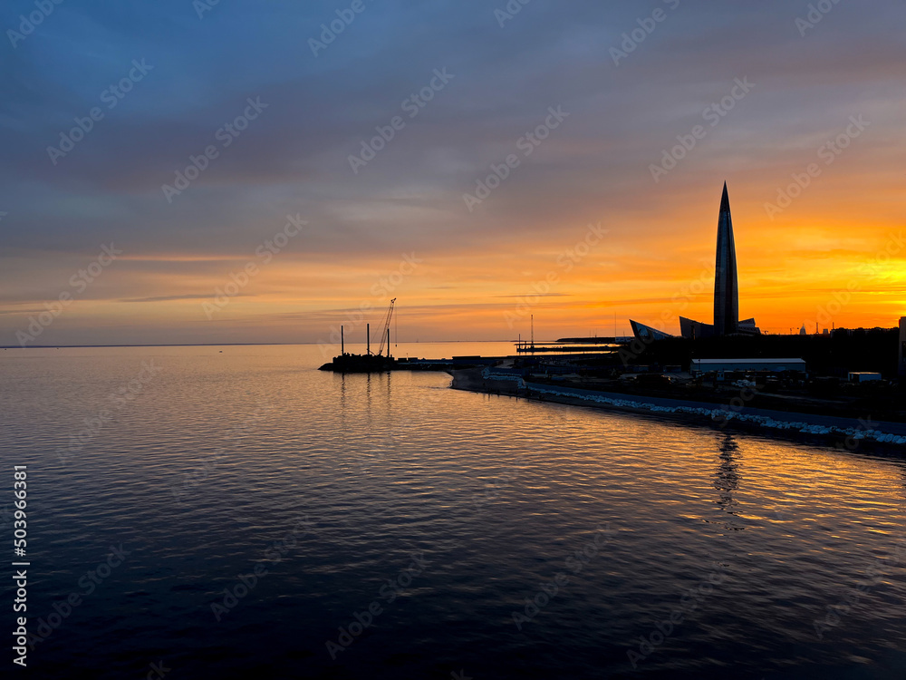 Fototapeta premium Sunset at the city sea coast, orange and purple sunset, sky reflection