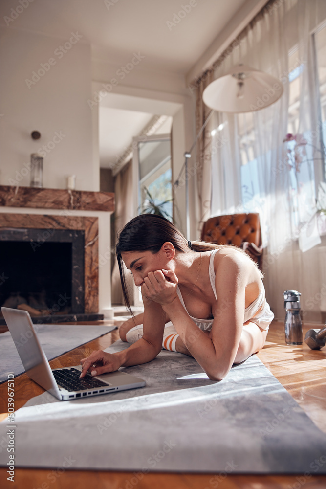 Pretty woman working out and making pause after exercise at home. Adult lady with beautiful shaped body exercising in the apartment.