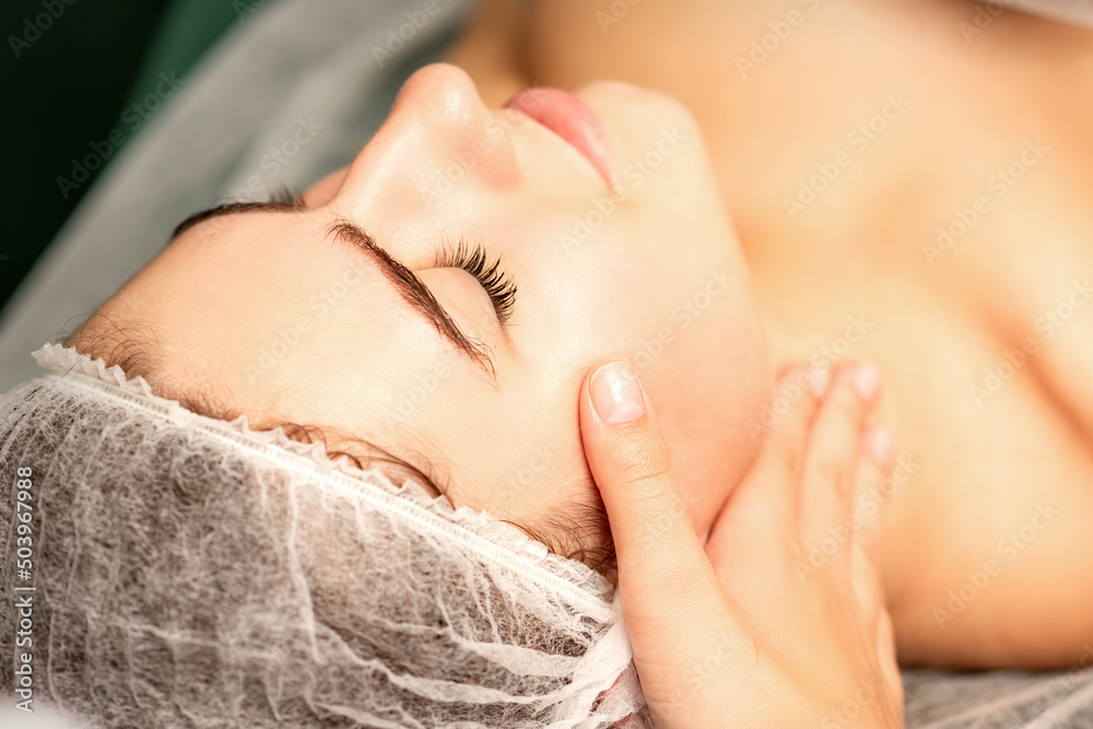 Facial massage. Hands of a masseur massaging neck of a young caucasian woman in a spa salon, the concept of health massage Facial massage. Hands of a masseur massaging neck of a young caucasian woman in a spa salon, the concept of health massage