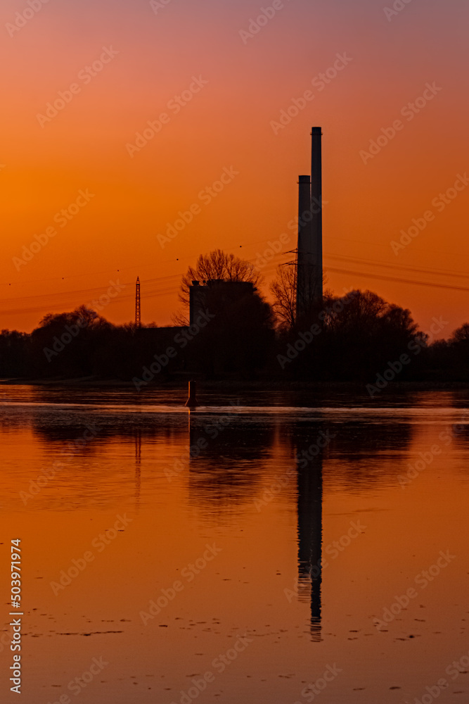 Beautiful sunset with reflections and a power plant silhouette near Pleinting, Danube, Bavaria, Germany