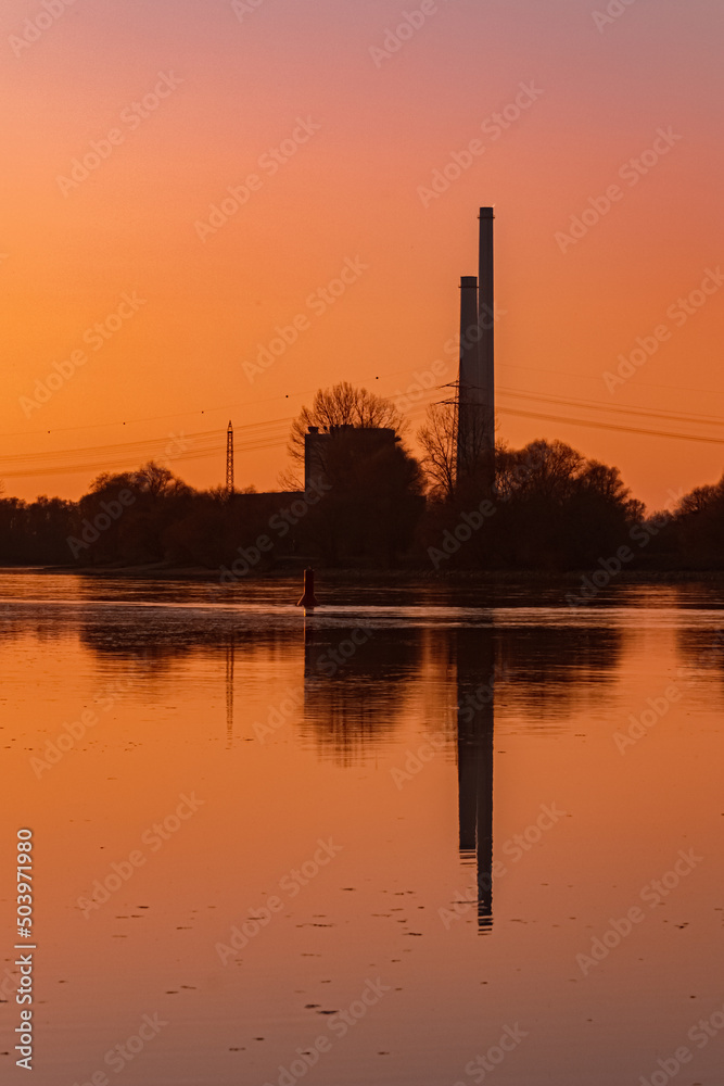 Beautiful sunset with reflections and a power plant silhouette near Pleinting, Danube, Bavaria, Germany