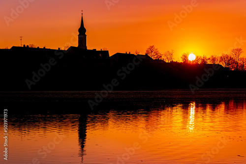 Beautiful sunset with reflections and a church silhouette near Pleinting, Danube, Bavaria, Germany