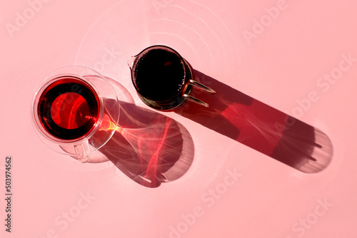 Refraction from tea cup and teapot on pink background, top view, light and shadow