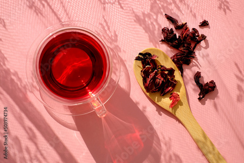 Tea cup and hibiscus tea, wooden spoon, top view. Light and shadow