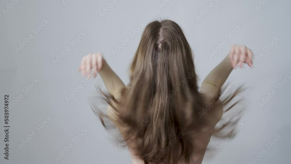 A young woman shaking her healthy hair. Back view
