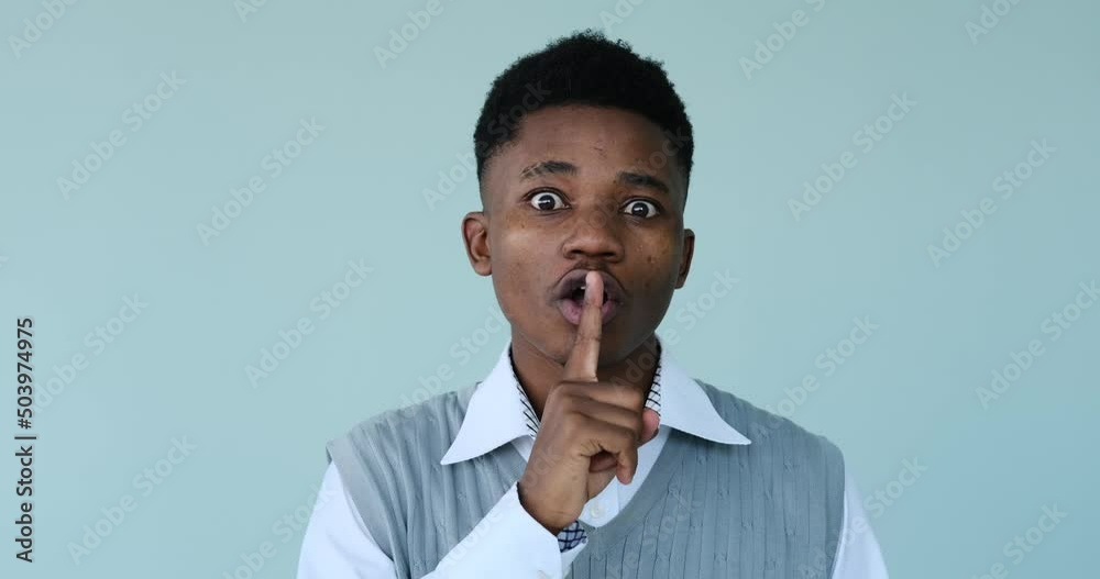 African American man gesturing with finger on lips over white background African American man gesturing with finger on lips over white background