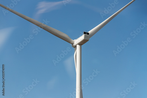 Closeup detail back view of new white modern wind turbine farm power generation station against clear blue sky on day time. Clean sustainable zero emission alternative electricity windfarm industry © Kirill Gorlov
