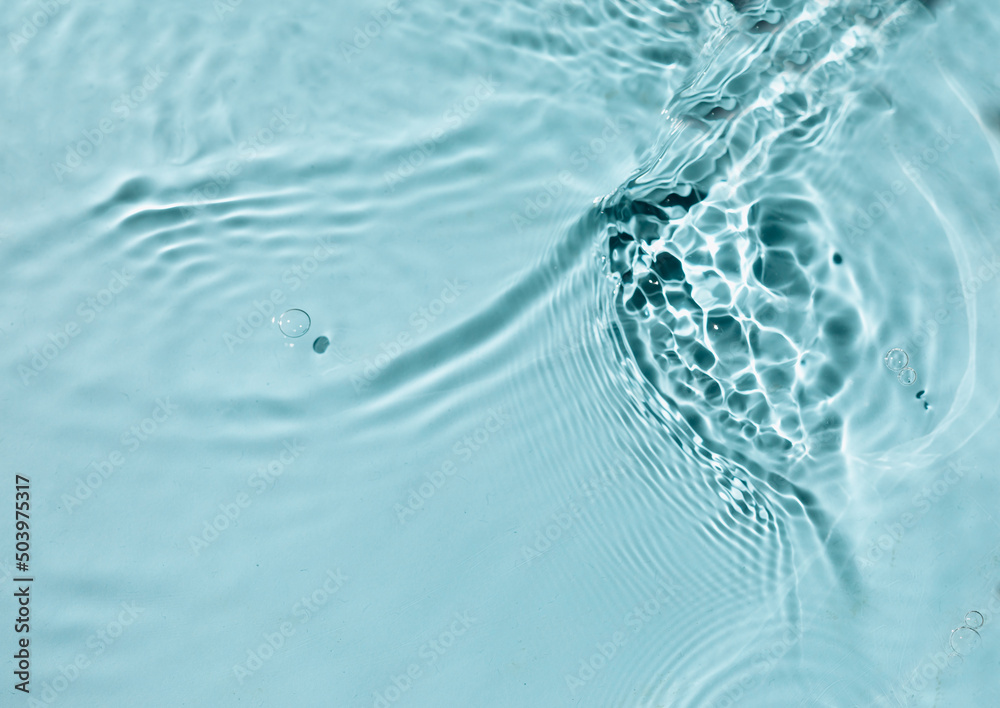  Liquid colored clear water surface texture with splashes bubbles.  Blue water waves in sunlight background.