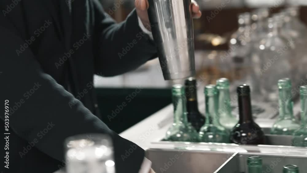 Professional bartender adds ice to shaker to make an authors cocktail