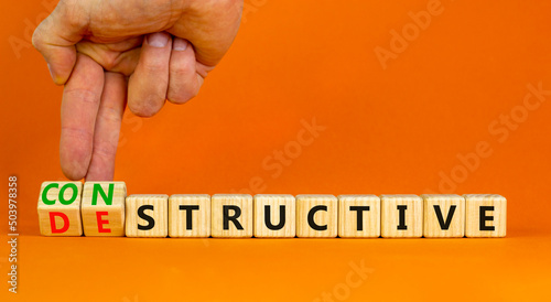 Destructive or constructive symbol. Businessman turns cubes changes the concept word Destructive to Constructive. Beautiful orange background. Business constructive destructive concept. Copy space. photo