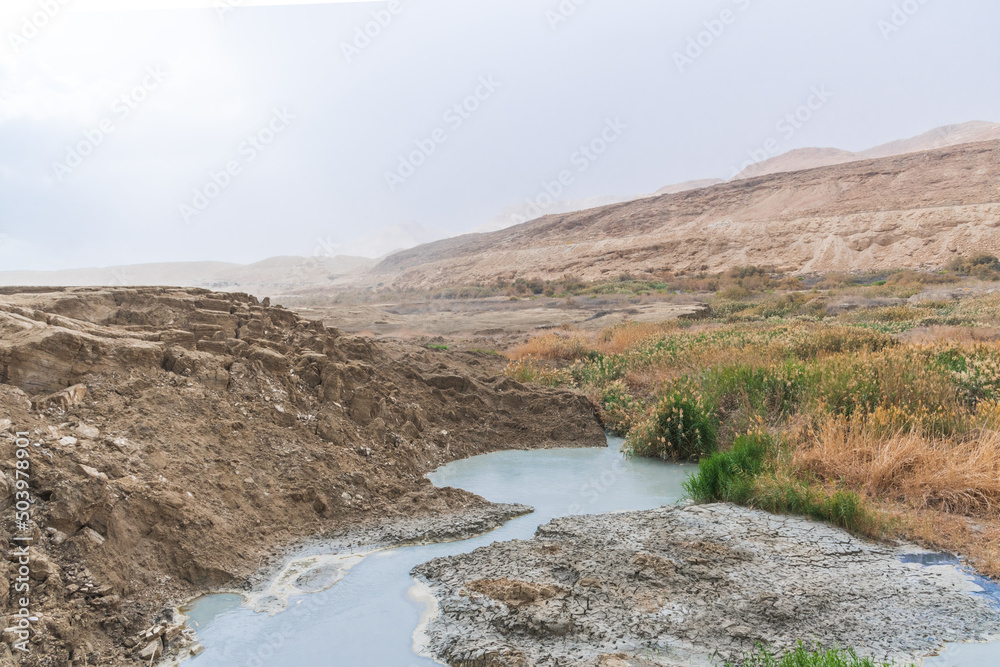 Sinkhole filled with turquoise water, near Dead Sea coastline. Hole formed when underground salt is dissolved by freshwater intrusion, due to continuing sea-level drop. . High quality photo