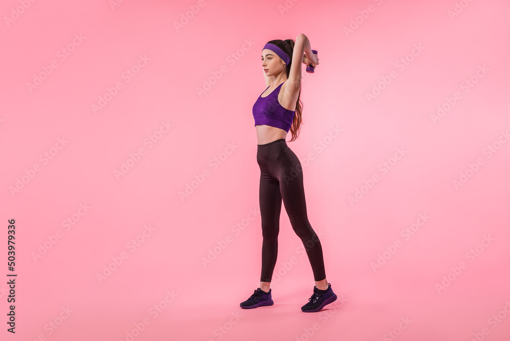 Athletic girl training with dumbbells on colorful pink background Athletic girl training with dumbbells on colorful pink background
