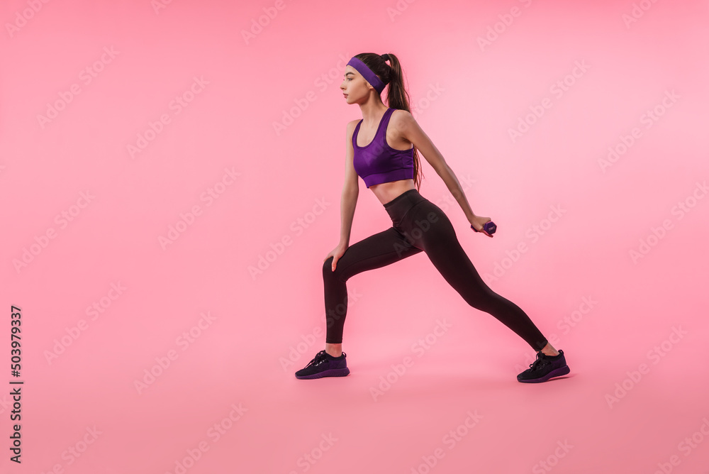 Sportswoman in leggings and top training with dumbbells