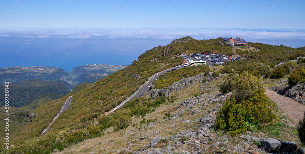 Panorama of Achada do Teixeira, plateau with refuge, natural rock formations and a trail to the nearby Pico Ruivo, the highest peak in Madeira Island. Clouds and  the Atlantic Ocean at the background.