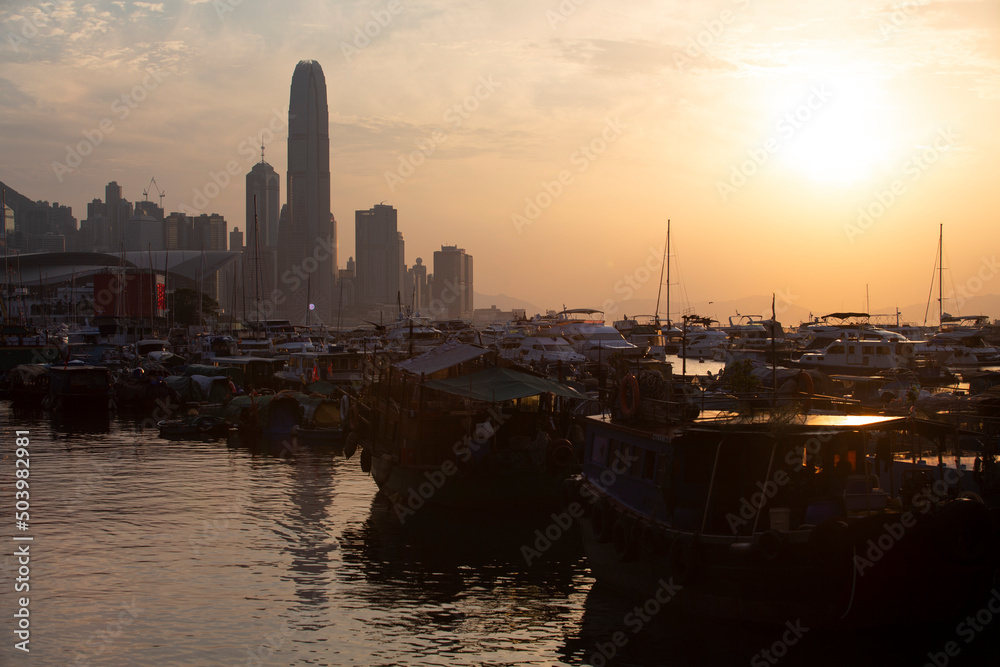 Naklejka premium junk boats with the backlit of skyscrapers in Hong Kong island, the view of typhoon shelter