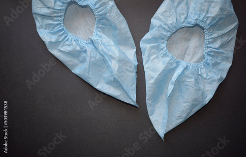 Shoe covers - covers or protective stockings worn over shoes. Medical disposable blue boot covers on a black background. 