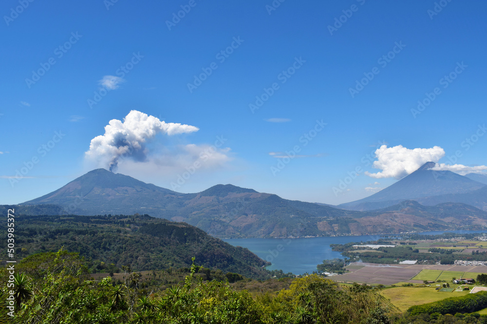 Panorámica del volcán Pacaya haciendo erupción al lado izquierdo, al lado derecho el volcán de agua y en la parte de abajo el lago de Amatitlán en Guatemala.