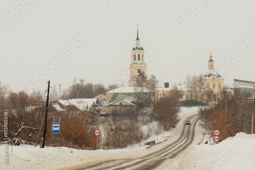 Winter, village orthodox church rises above the village and the road