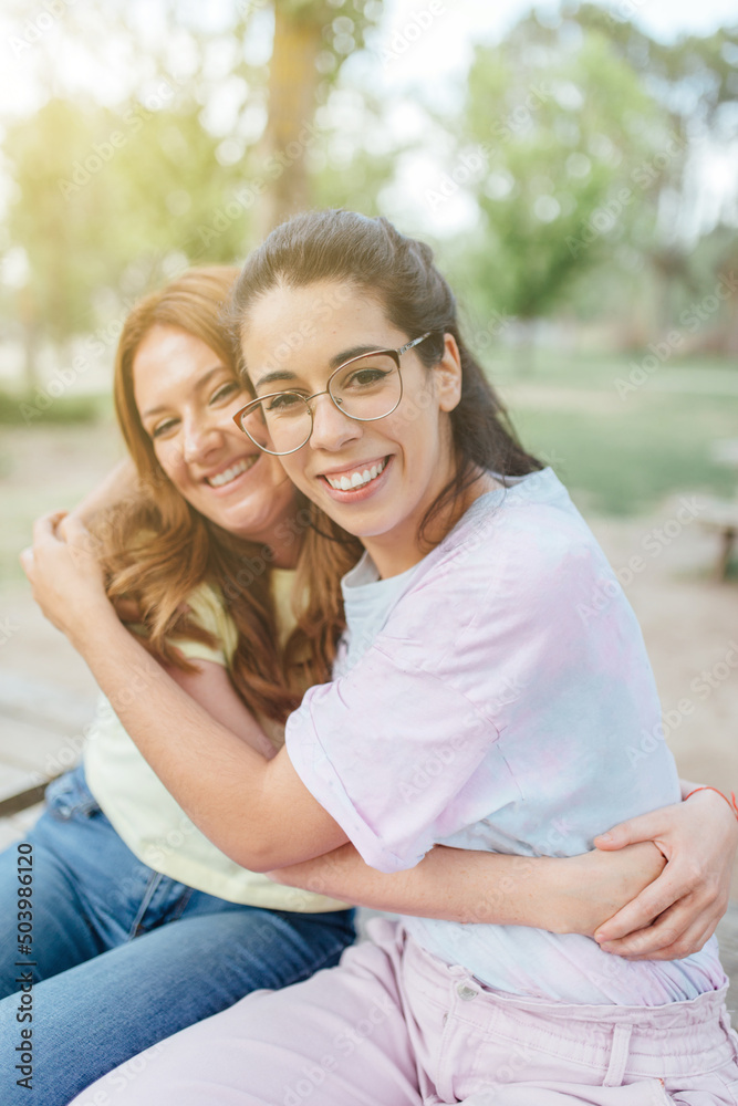 Naklejka premium Two happy girlfriends embracing looking at camera smiling
