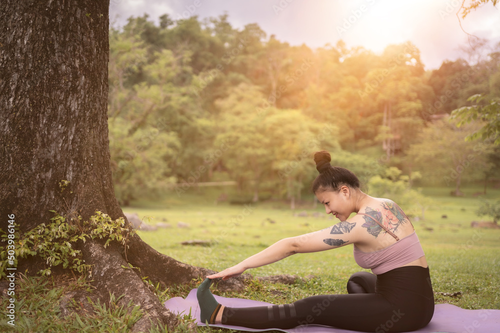 asian tattoo young woman doing yoga in the park