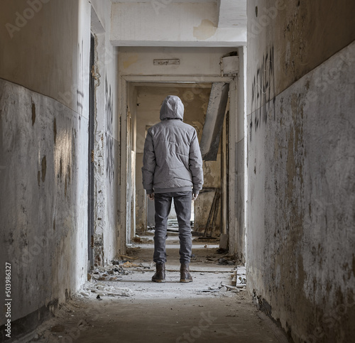 Man stands in an abandoned corridor. Rear view of man standing in corridor at abandoned building. 