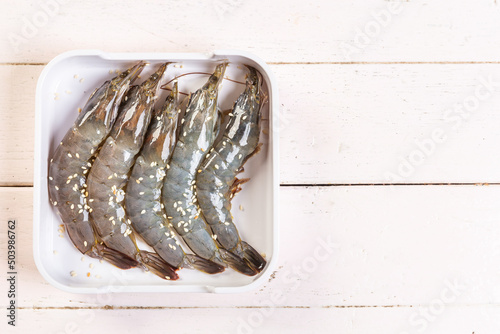 Fresh raw shrimps  top view in white plate, prinkle with white sesame on the table. photo