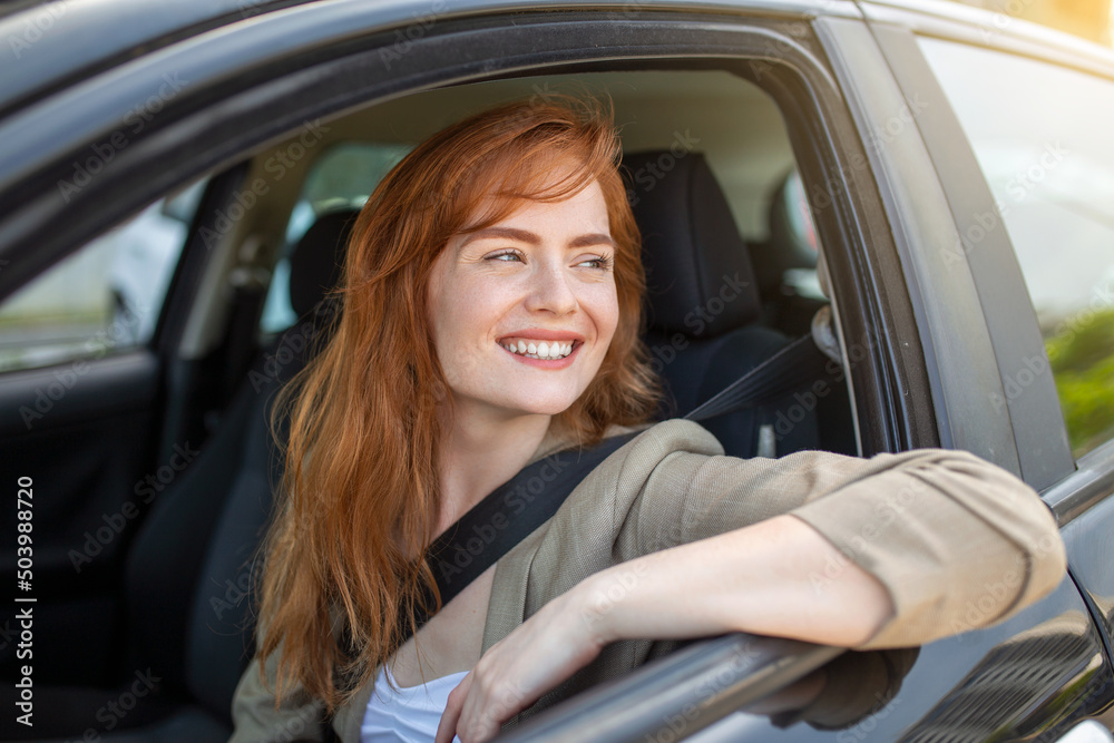 Beautiful young woman driving her new car at sunset. Woman in car. Close up portrait of pleasant looking female with glad positive expression, woman in casual wear driving a car - obrazy, fototapety, plakaty 