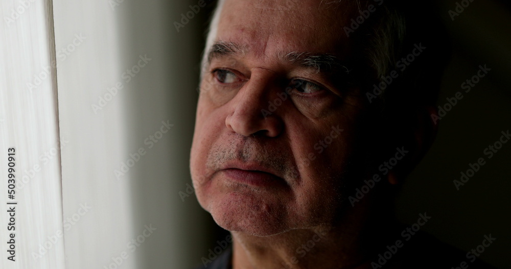 Contemplative older man standing by window thinking. Thoughtful sad depressed senior person Contemplative older man standing by window thinking. Thoughtful sad depressed senior person