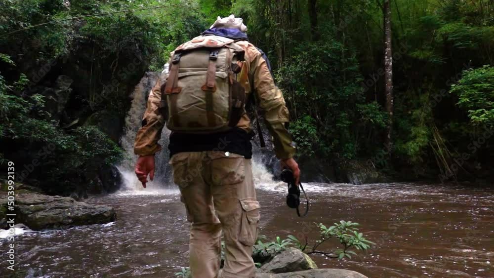 Male hiker walks to a waterfall on the plateau, raises his hand, enjoying nature and life. Mountain travel, adventure trips, lifestyle concepts Male hiker walks to a waterfall on the plateau, raises his hand, enjoying nature and life. Mountain travel, adventure trips, lifestyle concepts