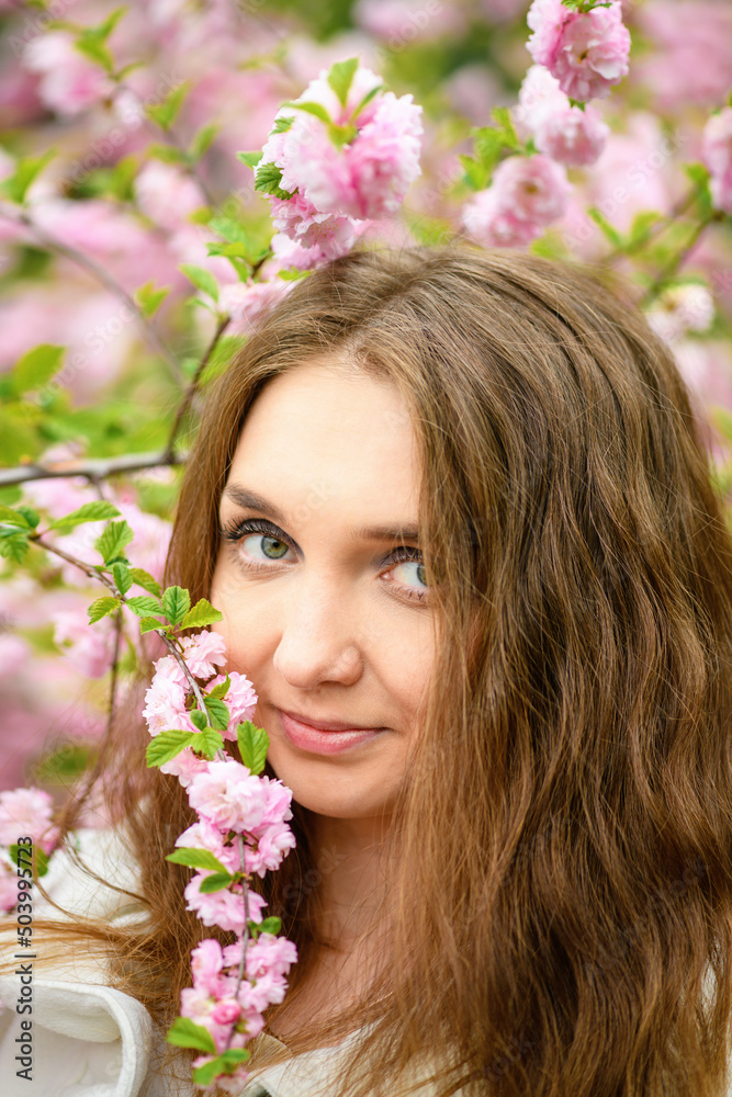 Beautiful girl and blooming garden, portrait. Girl in white coat with blooming sakura, apple tree Beautiful girl and blooming garden, portrait. Girl in white coat with blooming sakura, apple tree