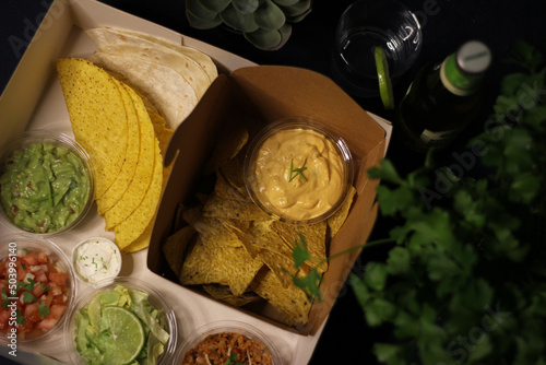 Mexican food box, tex mex, Taco, chili, tortilla, nachos chips, cheddar cheese, guacamole, sour cream, lettuce, tomato