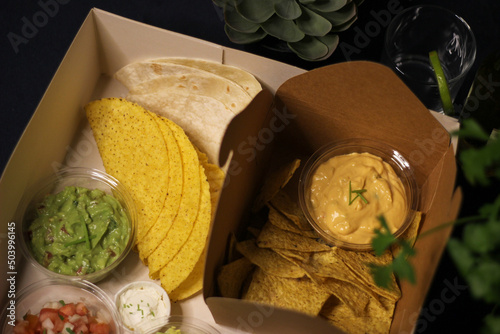 Mexican food box, tex mex, Taco, chili, tortilla, nachos chips, cheddar cheese, guacamole, sour cream, lettuce, tomato