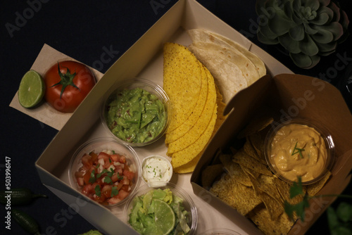 Mexican food box, tex mex, Taco, chili, tortilla, nachos chips, cheddar cheese, guacamole, sour cream, lettuce, tomato
