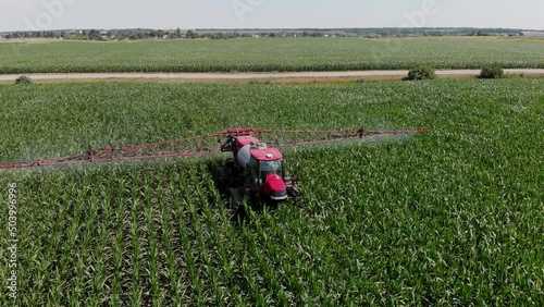 A tractor sprayer sprays corn in the field. Shooting from a 4K drone. Spraying of chemical fertilizers on an agricultural field