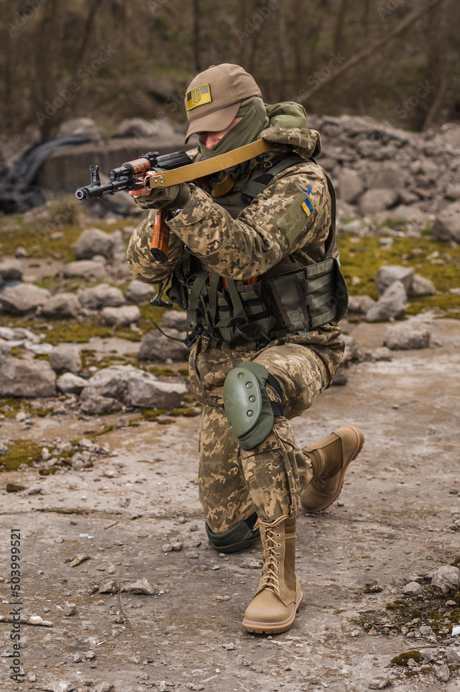Fototapeta premium Ukrainian soldier of the Armed Forces of Ukraine sits taking aim