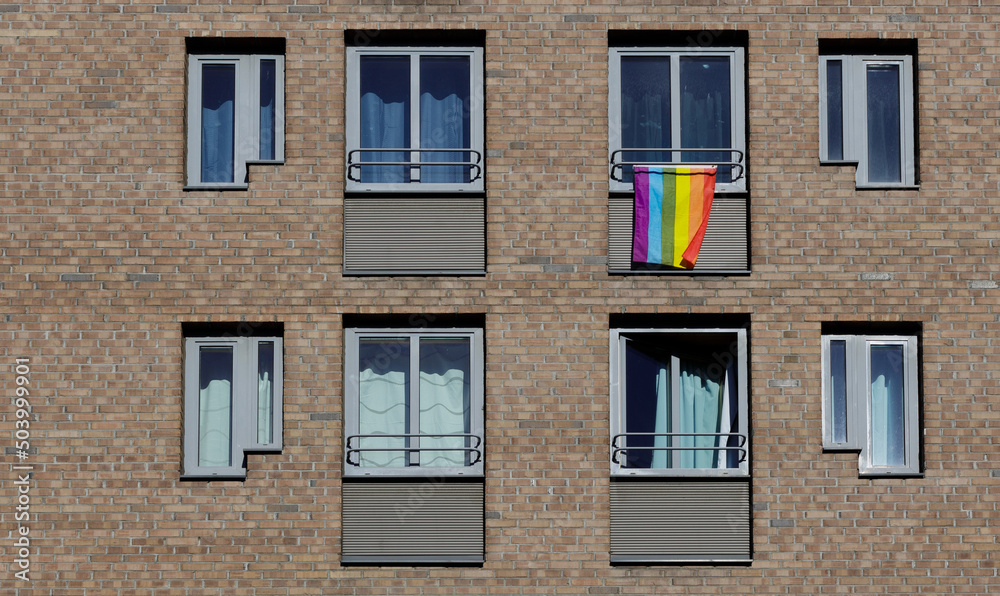 Rainbow flag on windows of house building on street in colors of gay lgbt lesbians.