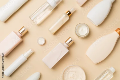 Obraz Different cosmetic bottles and container on color background, top view