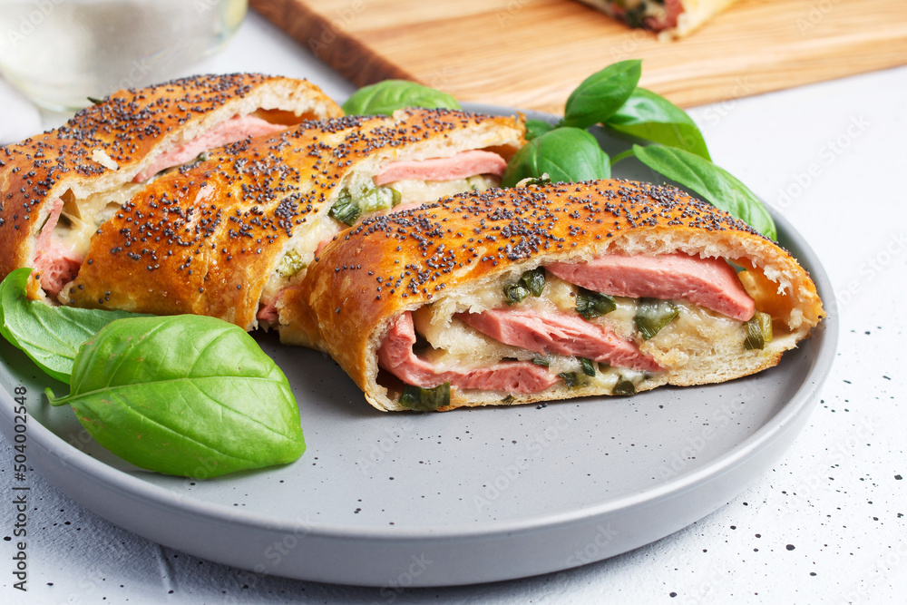 Traditional Italian stromboli stuffed with cheese, salami, green onions, sprinkled with poppy seeds.