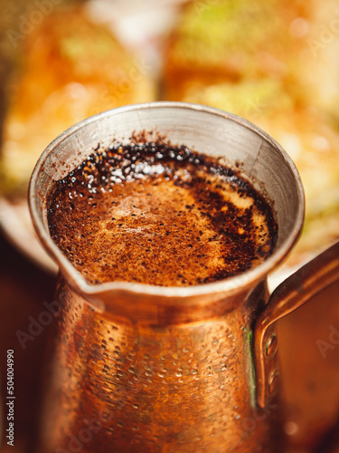 Close-up of freshly brewed oriental coffee in cezve. View from above photo