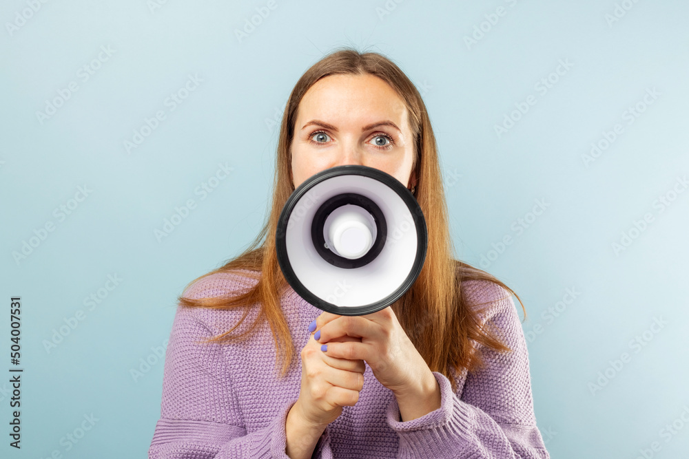 Young brunette woman shouting loudly while holding a megaphone on blue background. Concept of speech and announce, idea for marketing or sales Young brunette woman shouting loudly while holding a megaphone on blue background. Concept of speech and announce, idea for marketing or sales