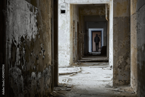 Man stands in abandoned corridor. Rear view of man standing in corridor at abandoned building © Live heavenly