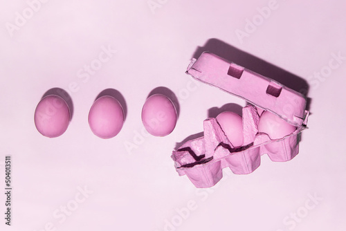 Pastel pink eggs in carton on light background. Creative monochromatic food concept. Minimalistic Easter composition.