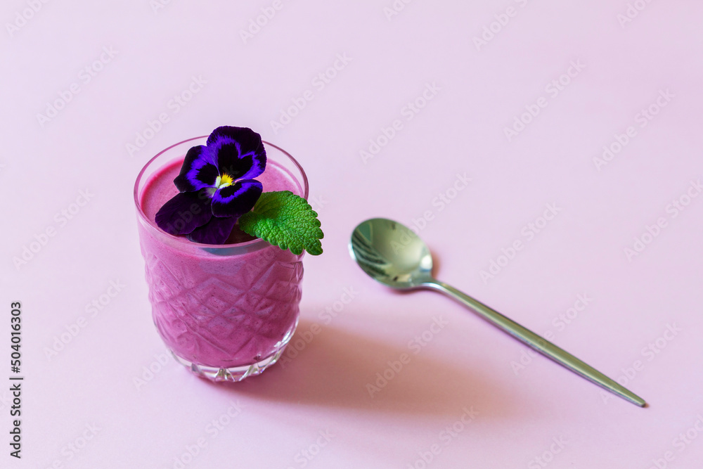 Blackcurrant berry mousse garnished with viola flower and lemon balm leaf.