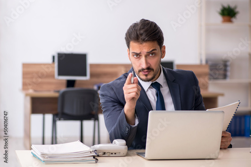 Young male employee sitting at workplace