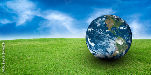 Earth Planet in green Field of Grass with Blue Sky Background. Copy space. Ecology and sustainability Concept 