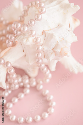 Pearl beads close up on shell on pastel pink background